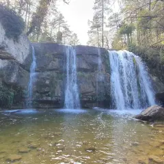 Cascada en la ruta 7 gorgs, con rocas cubiertas de musgo y vegetación, y un río de aguas claras.