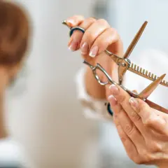 Manos de estilista sostienen tijeras de entresacar, listas para crear puntas desfiladas y dar forma a un corte moderno.