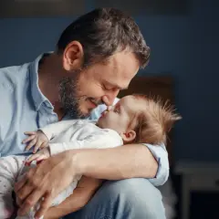 Szczęśliwy ojciec tuli swoje dziecko, ciesząc się urlopem ojcowskim.