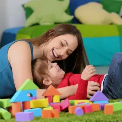 Uśmiechnięta opiekunka bawi się klockami z rocznym dzieckiem. Zastanawiasz się, ile kosztuje niania do rocznego dziecka?