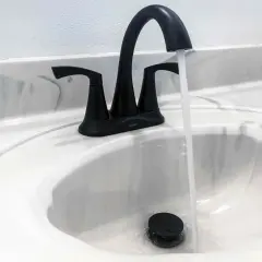 Rubinetto nero moderno in un lavandino bianco, con acqua che scorre. Uno stilema fad che aggiunge un tocco di eleganza.