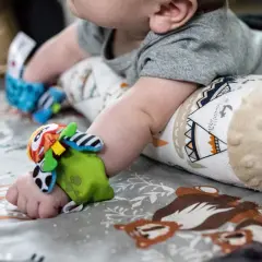 Kolorowe zabawki na rączkach i nóżkach malucha, idealne zabawy dla 6 miesięcznego dziecka na miękkiej macie z motywem zwierzątek.