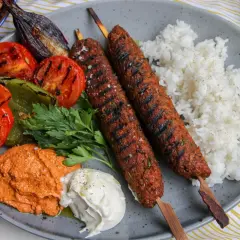 Saftiga kebabspett i ugn serveras med ris, grillade grönsaker och en krämig röra. En härlig måltid!
