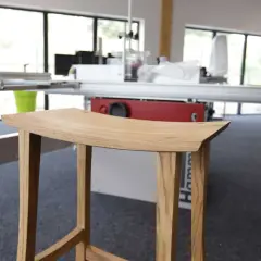 Tabouret en bois, œuvre d'un artisan utilisant un combiné bois Hammer. Lignes épurées, bois naturel.