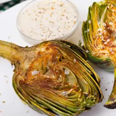 Alcachofas gratinadas con queso, tiernas y doradas, listas para disfrutar con una cremosa salsa.