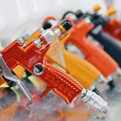 Rząd kolorowych pistoletów lakierniczych, w tym pomarańczowy z napisem "4600 Xtreme". Ustawienia pistoletu lakierniczego są kluczowe dla precyzyjnego malowania.