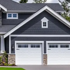 Maison moderne avec extension de garage double, bardage gris, pierres apparentes et toit sombre.