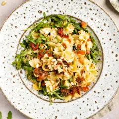 Mediterraner Salat mit Farfalle, Rucola, getrockneten Tomaten und Pinienkernen. Ein leichter Genuss!