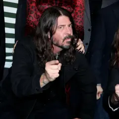 Dave Grohl z zespołu Foo Fighters wskazuje palcem, otoczony przez członków grupy.
