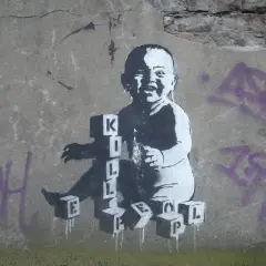 Dziecko bawi się klockami z literami, tworząc napis "KILL". To mocne co to jest graffiti, które prowokuje do myślenia.