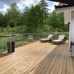 Ny slipad trall på altanen med solstolar och grill, redo för sommarens njutning i grönskan.