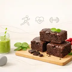 Zdrowe brownie z mąki pełnoziarnistej, zielony koktajl, maliny i akcesoria do ćwiczeń. Idealne połączenie przyjemności i aktywności.