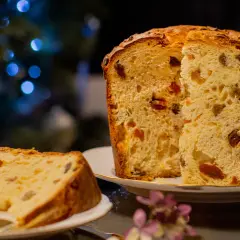 Pyszne babki włoskie z bakaliami, idealne na święta, na talerzyku obok choinki z niebieskimi lampkami.