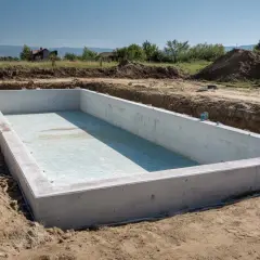 Betonowa niecka basenowa w wykopie. Zastanawiasz się, ile kosztuje wykopanie basenu? To dopiero początek inwestycji.
