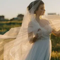 Novia con velo ondeando al atardecer, como si soñara con vestido de novia en un campo.