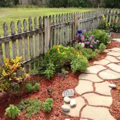 Ein geschwungener Steinweg führt durch einen blühenden Garten. Perfekt, um einen neuen Gartenweg anzulegen.