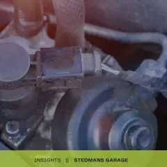 Zbliżenie na elementy silnika samochodowego, w tym złącze elektryczne i żółtą zakrętkę.
