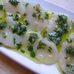 Délicieux carpaccio de saint jacques crues, nappé d'une vinaigrette aux herbes fraîches et à l'ail. Un plat léger et savoureux.