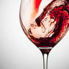 Vortice di vino rosso in un calice, con bollicine che rivelano la presenza dei tannini, responsabili della sensazione di astringenza.