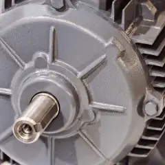 Dettaglio di un motore elettrico grigio, con albero motore visibile e una targhetta dorata.