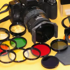 Una macchina fotografica con una varietà di filtri colorati (rossi, gialli, verdi, arancioni, blu) pronti per essere utilizzati per effetti creativi.