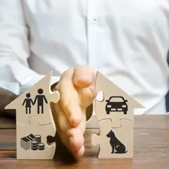Dwa domy z puzzli rozdzielone ręką. Jeden symbolizuje rodzinę i pieniądze, drugi auto i psa. Ilustracja sytuacji, kiedy ustaje wspólność majątkowa.