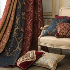 Rideau et coussins aux motifs **damassés** dorés sur fond bleu marine et rouge. Un fauteuil élégant complète la scène.