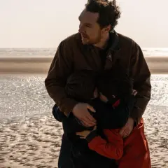 En man kramar sina barn på stranden. En scen som känns som en av de där comfort movies man vill se om och om igen.