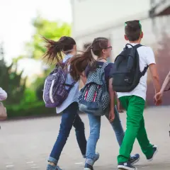 Dzieci z plecakami biegną na zakończenie roku szkolnego 2026. Radość i wolność widać w ich krokach.