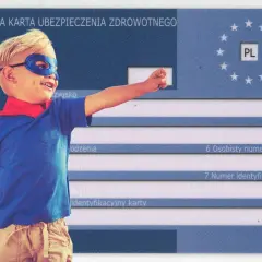 Chłopiec w stroju superbohatera na tle Europejskiej Karty Ubezpieczenia Zdrowotnego. Czy karta EKUZ działa w Turcji? Tak, zapewnia ochronę.