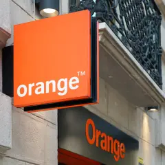 Pomarańczowy znak z napisem "orange" i logo multinagrywarka orange na fasadzie budynku.