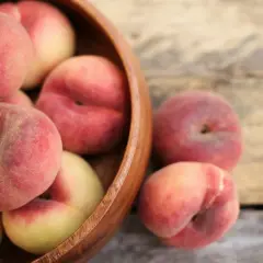 Nektarynki w drewnianej misce, idealne na zdrową przekąskę. Sprawdź, ile nektarynka kcal!