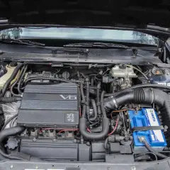 Silnik V6 wolnossący Peugeot, z widocznym akumulatorem Varta i elementami układu dolotowego.