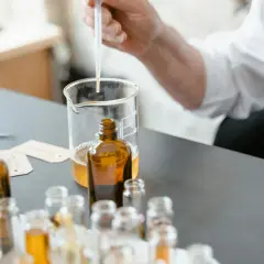 Ricerca su coumarin cos'è: un profumiere testa essenze in ambrate bottigliette, con un contagocce in un becher.