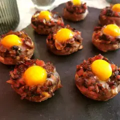 Champiñones rellenos con huevo y trocitos de tomate y cebolla, listos para disfrutar.
