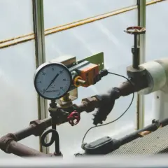 Manometr wskazuje prawidłowe ciśnienie w instalacji co. Rury i zawory są widoczne.