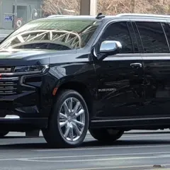 Czarny Chevrolet Suburban, który wygląda jak największe auto na świecie, z chromowanymi felgami i błyszczącą atrapą chłodnicy.