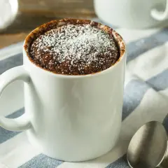 Un delizioso mug cake al cioccolato, spolverato di zucchero a velo, pronto per essere gustato.