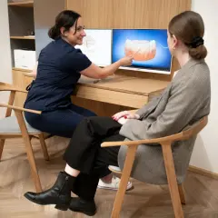 Dentystka pokazuje pacjentce na ekranie, jak prawidłowo dbać o higienizację zębów.