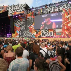 Tłum ludzi na koncercie Pol'and'Rock przed sceną z wielkim ekranem i grafikami.