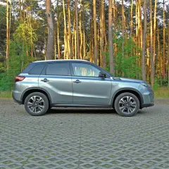 Szary Suzuki Vitara 2023 zaparkowany na tle sosnowego lasu.