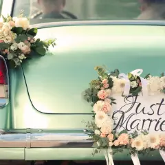 Hochzeitsauto mit Blumen geschmückt, "Just Married" Schild. Ein besonderer Urlaub nach der Hochzeit, vielleicht mit einem Kind auf dem Weg.