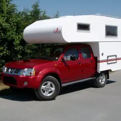 Un camping-car increvable rouge, prêt pour l'aventure. Sa cabine blanche offre un espace de vie confortable pour explorer le monde.