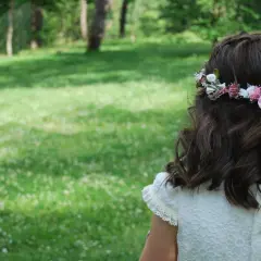 Niña con corona de flores y listones rosas, un ejemplo de peinados para niñas fáciles y bonitos.