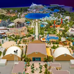 Maquette détaillée d'un parc d'attractions Disney avec lac, montagnes, bâtiments et attractions.