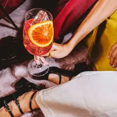 Elegancka kobieta z drinkiem, w którym widać plaster pomarańczy i lód. To może być wermut, co to za napój?