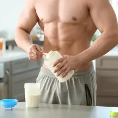 Muskulöser Mann bereitet Proteinshake zu. Informiere dich über mögliche proteinpulver nebenwirkungen, bevor du es verwendest.