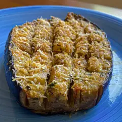 Melanzane a barchetta ripiene e gratinate, pronte per essere gustate su un piatto blu.