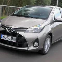 Szary Toyota Yaris w ruchu drogowym, widok z przodu.