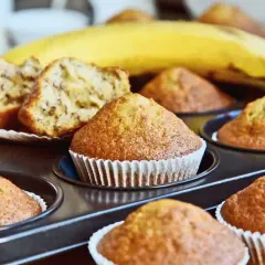 Muffin alla banana appena sfornati nella friggitrice ad aria, con una banana matura sullo sfondo.